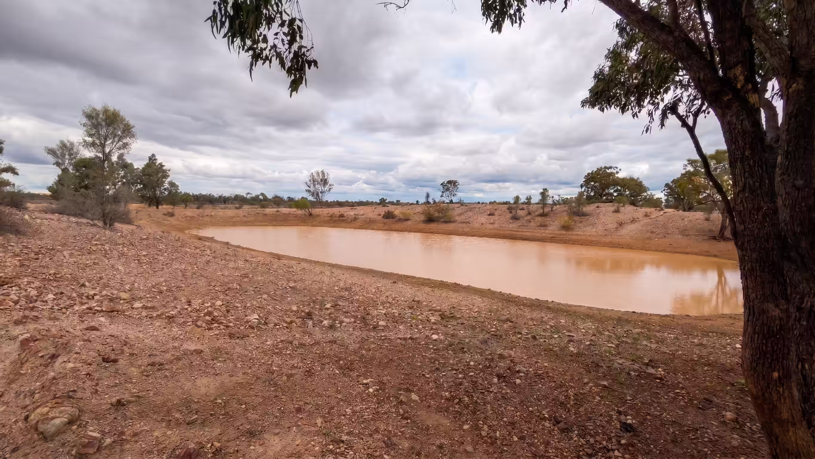 Deep earthen stock water dam under open Queensland sky